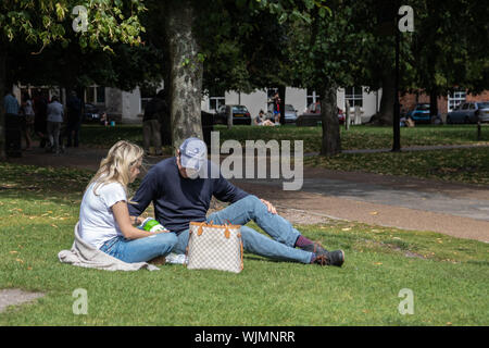 Ein paar Sat im Park auf der Wiese in der Sonne an einem Sommertag mit Mittagessen Stockfoto