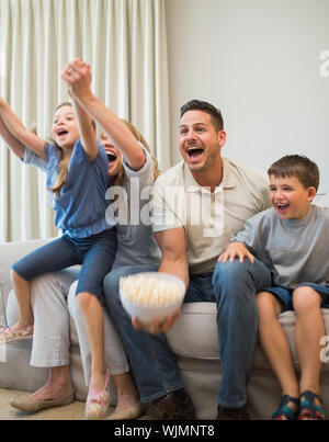 Familie aufgeregt schreien beim Fernsehen auf dem Sofa zu Hause Stockfoto