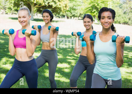 Group Portrait von zuversichtlich sportliche Frauen heben die Hände Gewichte im Park Stockfoto