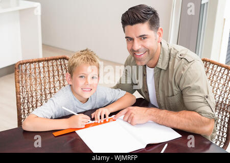 Lächelnd Vater Sohn helfen bei den Hausaufgaben zu Hause am Tisch in der Küche Stockfoto