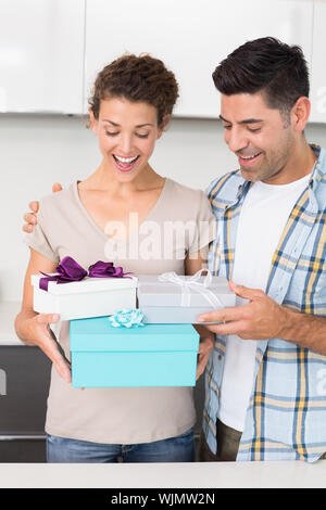 Überrascht Frau mit vielen Geschenken von ihrem Partner zu Hause in der Küche Stockfoto