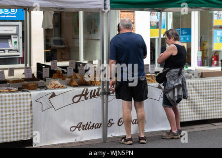 Winchester, Hampshire, UK ein Paar mittleren Alters auf das Essen auf der Suche nach Verkauf auf einem Marktstand Stockfoto