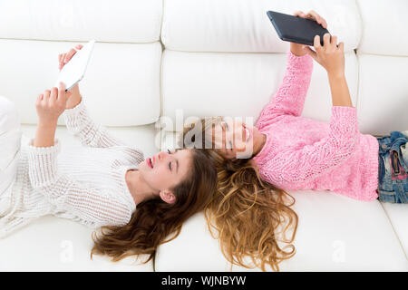 Freunde Kinder Kind Mädchen, die Spaß mit Tablet-pc auf weißen Sofa liegend spielen Stockfoto