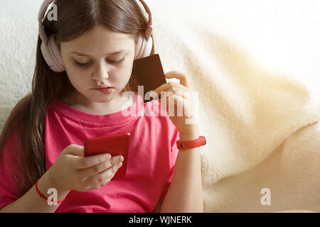 Junge schöne jugendlicher Mädchen in der Kopfhörer sitzt auf einem Sofa Stockfoto