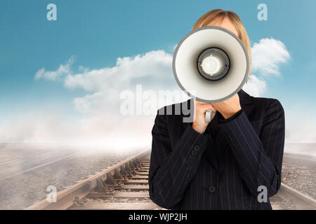 Nahaufnahme einer Geschäftsfrau mit einem Megafon ihr Gesicht gegen Zug Titel über dem Horizont führende ausblenden Stockfoto