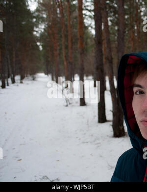 7/8 Image der jungen Mann auf schneebedeckter Fußweg von Bäumen im Wald