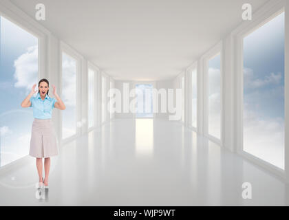 Überrascht stilvolle Geschäftsfrau gegen helle weiße Halle mit Windows posing Stockfoto