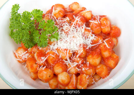 Ansicht von oben Weiße Schüssel mit grünen Ring um Kante mit frischen, hausgemachten Gnocchi in marinara Sauce überzogen und mit frisch geriebenem Parmesan garniert Stockfoto