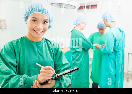 Lächelnde Frau Chirurgen schreiben operative Patientenakten Stockfoto