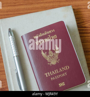 Thai Pass mit Notebook auf Holztisch Hintergrund Stockfoto