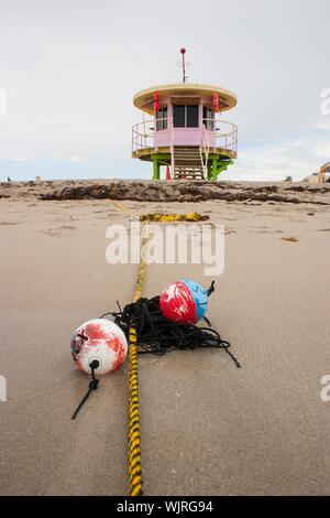 Vertikale Aufnahme von Bojen auf der sandigen Küste in der Nähe von A Rettungsschwimmer Turm Stockfoto