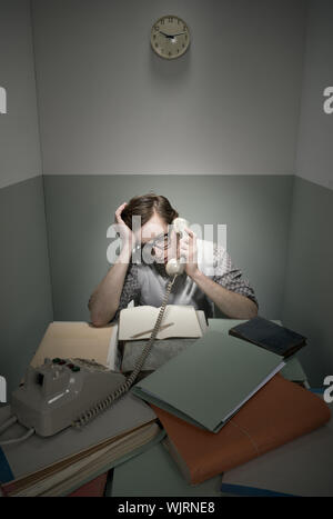 Retro-Geek am Telefon mit unordentlichen Schreibtisch in einem kleinen Raum. Stockfoto