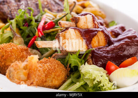 Gesunde platter gemischter Aufschnitt einschließlich gegrilltes Steak, knusprig panierte Hähnchen und Rindfleisch auf einem Bett von frischem grünem Salat serviert mit Französischen Stockfoto