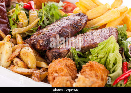 Gesunde platter gemischter Aufschnitt einschließlich gegrilltes Steak, knusprig panierte Hähnchen und Rindfleisch auf einem Bett von frischem grünem Salat serviert mit Französischen Stockfoto