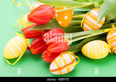 Bunte rote Ostern noch Leben mit zarten frischen Frühling Tulpen und Handbemalt traditionelle Ostereier angeordnet auf einem weißen Hintergrund mit copyspac Stockfoto