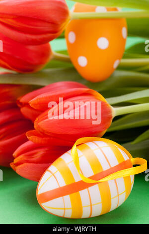 Bunte rote Ostern noch Leben mit zarten frischen Frühling Tulpen und Handbemalt traditionelle Ostereier angeordnet auf einem weißen Hintergrund mit copyspac Stockfoto