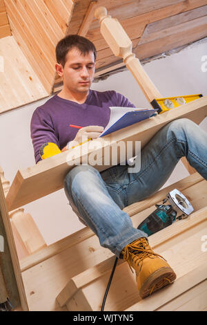 Arbeitnehmer schriftlich Zwischenablage mit Holzbrett an den Beinen Stockfoto