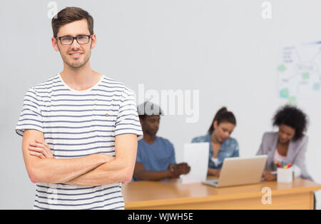 Porträt einer beiläufigen männliche Künstler mit Kollegen im Hintergrund an einem hellen Büro Stockfoto