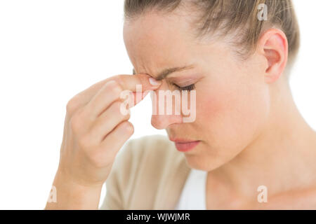 Frau mit Kopfschmerzen ihre Nase kneifen auf weißem Hintergrund Stockfoto