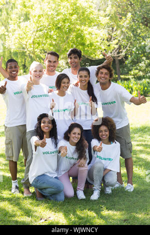 Group Portrait von zuversichtlich Freiwilligen zeigen Daumen hoch in Park Stockfoto