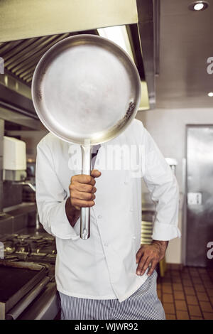 Männliche cook Holding pan vor seinem Gesicht in der Küche Stockfoto