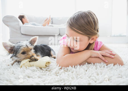 Kleines Mädchen liegen auf Teppich mit Yorkshire Terrier zu Hause im Wohnzimmer Stockfoto