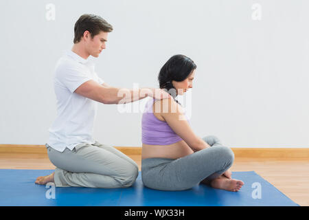 Masseur reiben schwangere womans schultern in einem Fitness Studio. Stockfoto