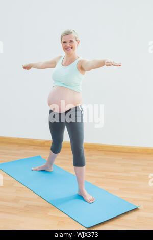 Blonde schwangere Yoga auf blauen Matten Lächeln auf die Kamera in ein Fitness Studio. Stockfoto