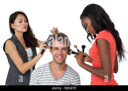 Assistenten der Anwendung Make-up zu männliches Modell auf weißem Hintergrund Stockfoto