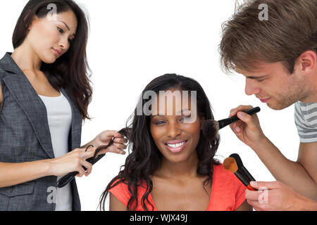 Assistenten der Anwendung Make-up zu einem weiblichen Modell auf weißem Hintergrund Stockfoto