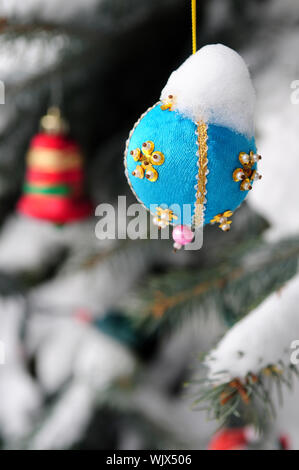 Weihnachtsschmuck hängen Schnee bedeckt Fichte außerhalb Stockfoto