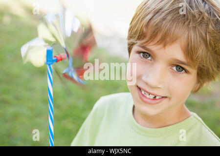 Nahaufnahme Porträt eines lächelnden Jungen holding Windrad im Park Stockfoto