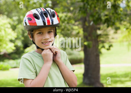 Porträt eines lächelnden Jungen tragen Fahrradhelm im Park Stockfoto