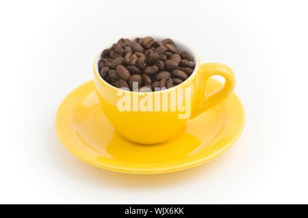Gelbe Espressotasse mit Kaffeebohnen gefüllt Stockfoto