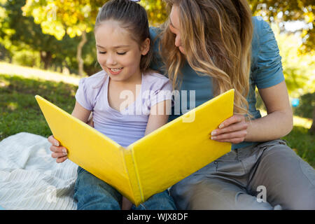 Glückliche Mutter und Tochter ein Buch lesen im Park Stockfoto