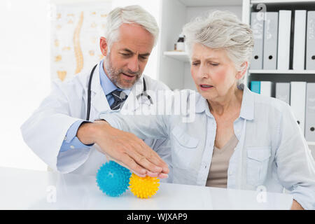 Männlicher Arzt mit älteren Patienten mit Stress Buster Kugeln an der medizinischen Büro Stockfoto