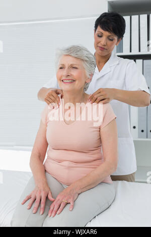 Weibliche Chiropraktor massieren ein älterer womans Schulter in der Arztpraxis Stockfoto