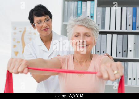 Weiblichen Physiotherapeuten massieren Senior womans zurück in der Arztpraxis Stockfoto