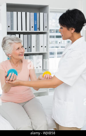 Ärztin mit älteren Patienten mit Stress Buster Kugeln an der medizinischen Büro Stockfoto