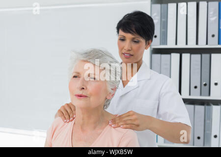 Weibliche Chiropraktor massieren ein älterer womans Schulter in der Arztpraxis Stockfoto