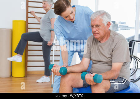 Therapeuten Unterstützung älterer Mann mit Hanteln in den medizinischen Büro Stockfoto