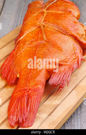 Leckeren geräucherten Fisch Full Body Red Snapper auf Schneidebrett closeup auf Holz- Hintergrund Stockfoto