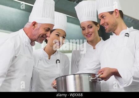 Team von Köchen bewundern, was in den Topf in eine kommerzielle Küche Stockfoto