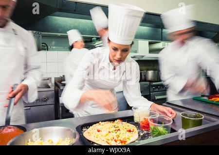 Fokussierte Küchenchef bereitet eine Pizza in einer gewerblichen Küche Stockfoto