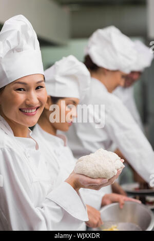 Happy Chef holding Teig bei Kamera lächelnd in einem kommerziellen Küche Stockfoto