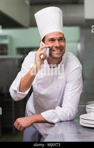 Happy Chef am Telefon zu sprechen in einer gewerblichen Küche Stockfoto