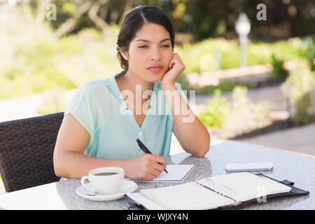 Seriöse Geschäftsfrau Kaffee und ihre Woche planen in Terrasse des Restaurants Stockfoto
