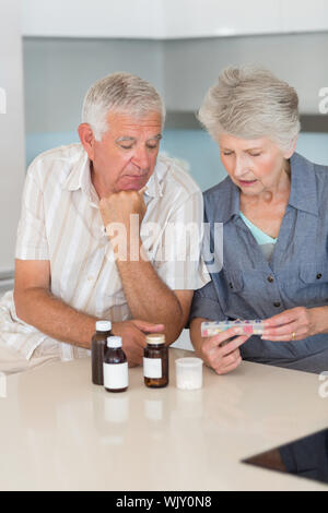 Senior Paar an, ihre Medizin zu Hause in der Küche auf der Suche Stockfoto