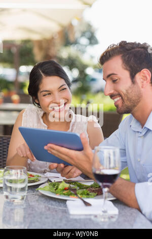 Glückliches Paar auf ein Datum über Tablet PC im Patio Restaurant Stockfoto
