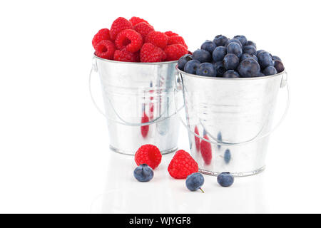 Heidelbeeren und Himbeeren Beeren in einem Blecheimer isoliert auf weißem Hintergrund Stockfoto